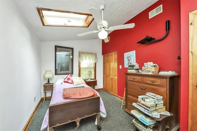 bedroom featuring lofted ceiling with skylight, carpet, visible vents, and a textured ceiling