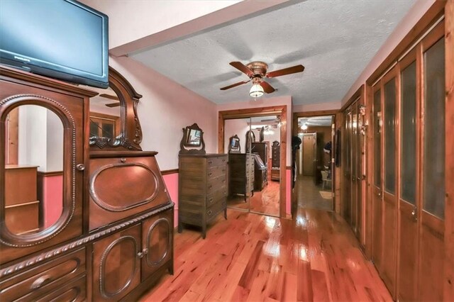 living room with light hardwood / wood-style floors, lofted ceiling with beams, a textured ceiling, and ceiling fan