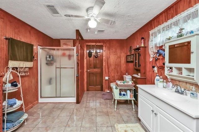 bathroom with tile patterned flooring, a shower stall, visible vents, and a textured ceiling