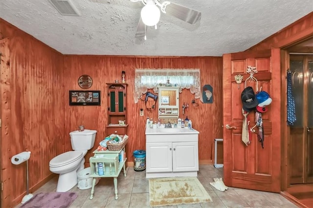 bathroom featuring visible vents, a ceiling fan, toilet, a textured ceiling, and vanity