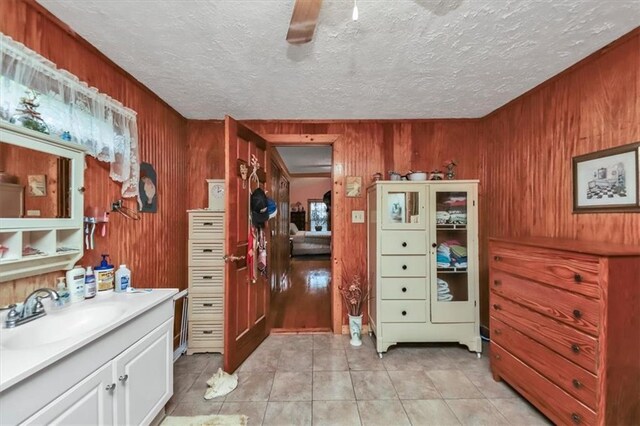 bathroom featuring ceiling fan, toilet, wood walls, vanity, and tile patterned flooring