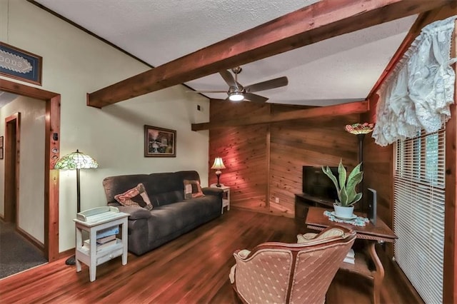 living room featuring vaulted ceiling with beams, a ceiling fan, wood walls, a textured ceiling, and wood finished floors