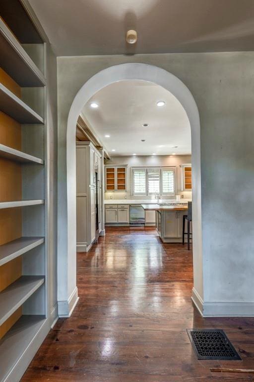 corridor with built in shelves and dark wood-type flooring