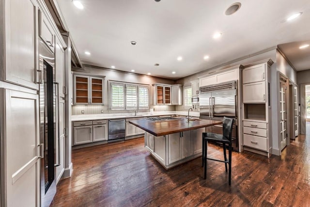 kitchen with sink, dark wood-type flooring, stainless steel appliances, butcher block countertops, and a kitchen island