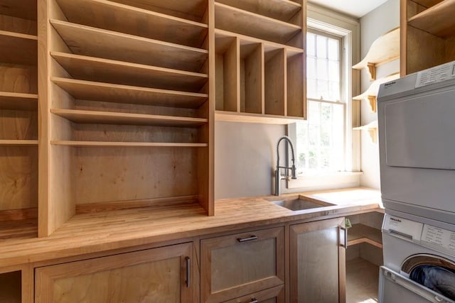 laundry room with cabinets, sink, and stacked washer and dryer