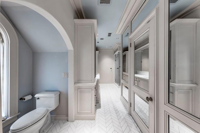 bathroom with toilet, crown molding, and a wealth of natural light