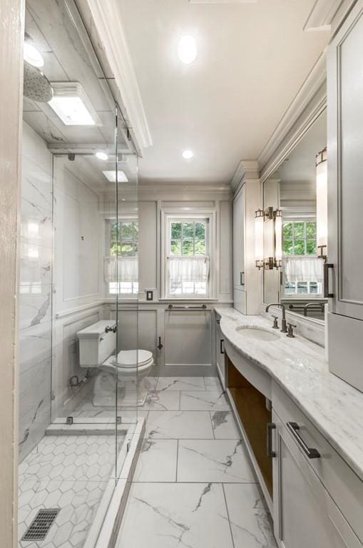 bathroom featuring vanity, toilet, a shower with door, and crown molding