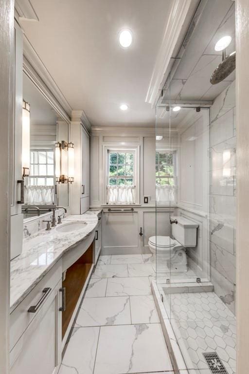 bathroom with vanity, toilet, a shower with shower door, and crown molding