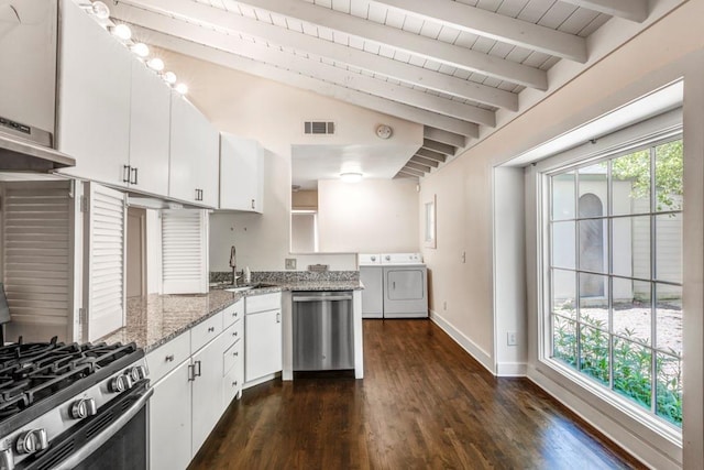 kitchen featuring a healthy amount of sunlight, dark stone counters, washer and clothes dryer, white cabinets, and appliances with stainless steel finishes