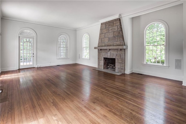 unfurnished living room featuring hardwood / wood-style flooring, a stone fireplace, and a wealth of natural light