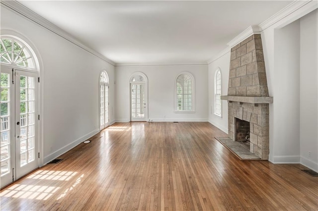 unfurnished living room with hardwood / wood-style floors, ornamental molding, a fireplace, and french doors