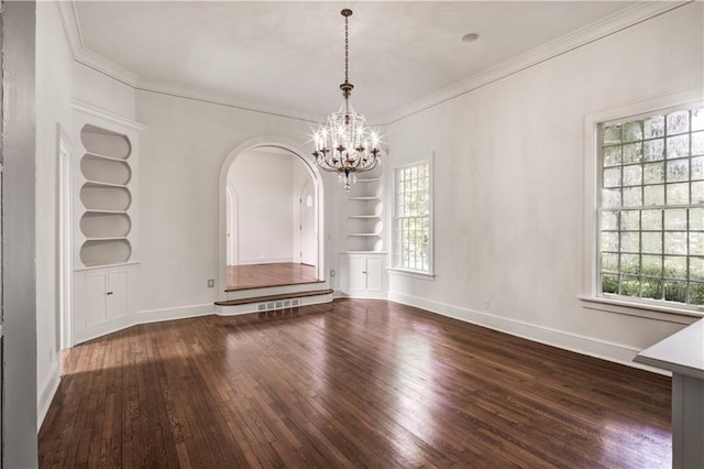 unfurnished dining area featuring dark hardwood / wood-style flooring, crown molding, built in features, and a chandelier