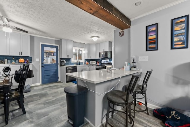 1467 Hewatt Rd, Lilburn, GA 30047 - kitchen featuring appliances with stainless steel finishes, a peninsula, a kitchen bar, backsplash, and ornamental molding