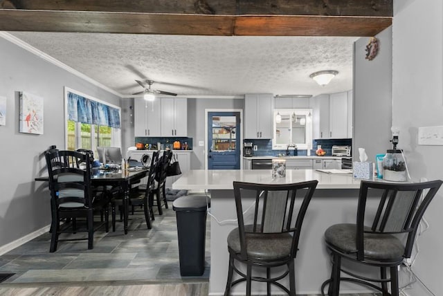 1467 Hewatt Rd, Lilburn, GA 30047 - kitchen with ornamental molding, a peninsula, decorative backsplash, a kitchen bar, and light countertops