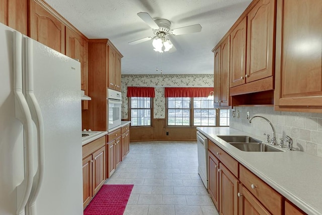 kitchen with sink, wooden walls, white appliances, and ceiling fan