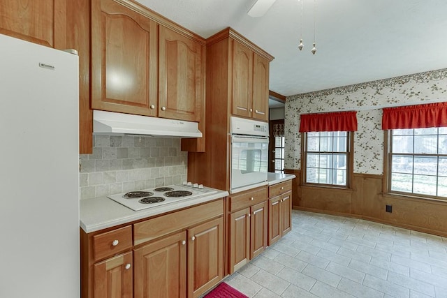 kitchen with white appliances, ceiling fan, and wooden walls