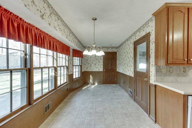 unfurnished dining area featuring wood walls and a chandelier