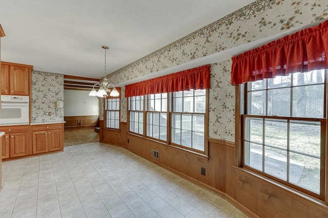 kitchen with hanging light fixtures, wooden walls, a chandelier, and oven