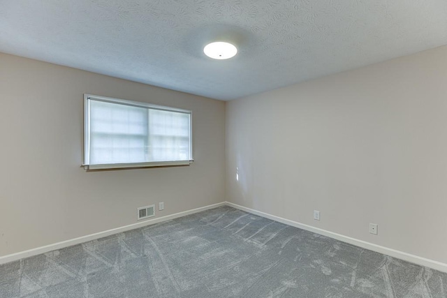 carpeted empty room with a textured ceiling