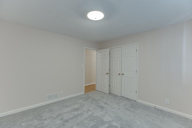 unfurnished bedroom with light colored carpet and a closet