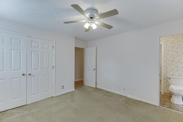 unfurnished bedroom with ceiling fan, a closet, and connected bathroom