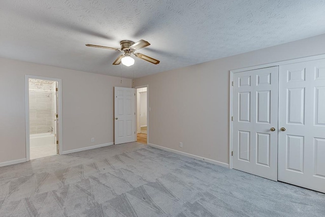 unfurnished bedroom featuring a closet, a textured ceiling, ceiling fan, and light colored carpet