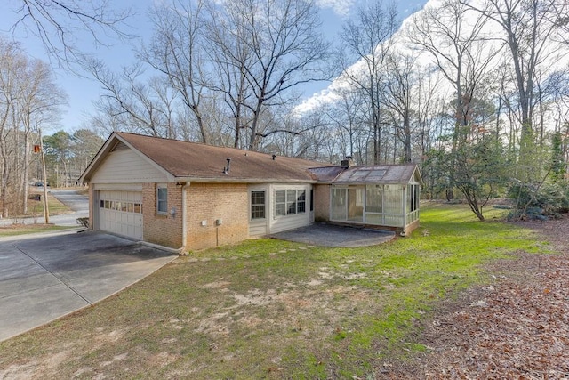 rear view of property with a sunroom, a yard, and a garage