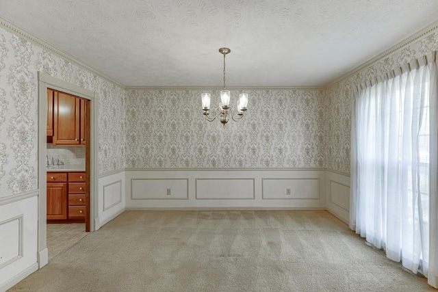 unfurnished dining area featuring a textured ceiling, a notable chandelier, crown molding, and light carpet