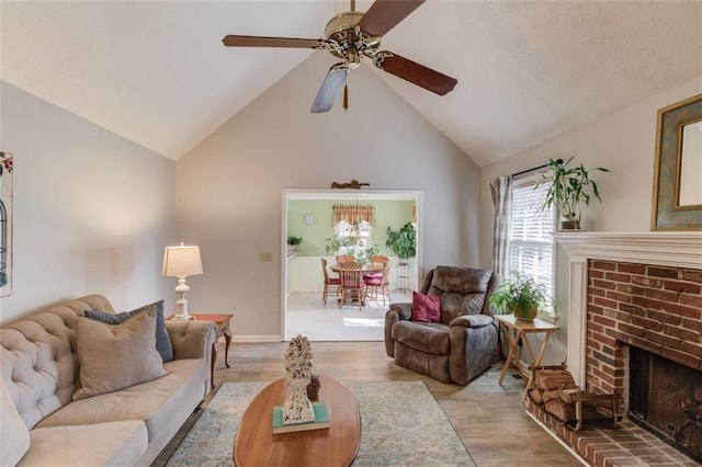 living room featuring lofted ceiling, a ceiling fan, a brick fireplace, wood finished floors, and baseboards