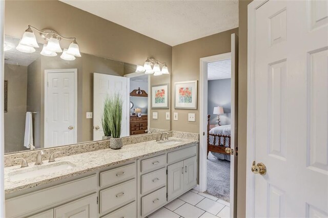 full bath with double vanity, ensuite bath, tile patterned flooring, and a sink