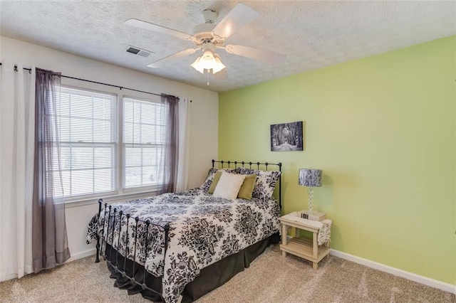 bedroom with carpet floors, visible vents, a textured ceiling, and baseboards