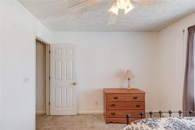 carpeted bedroom with ceiling fan, a textured ceiling, and baseboards