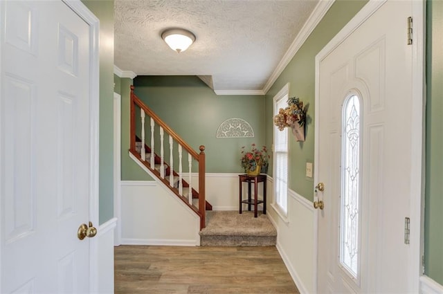 entrance foyer with crown molding, a textured ceiling, wood finished floors, baseboards, and stairs