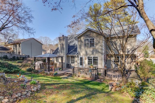 back of house featuring a chimney, fence, a lawn, and a wooden deck