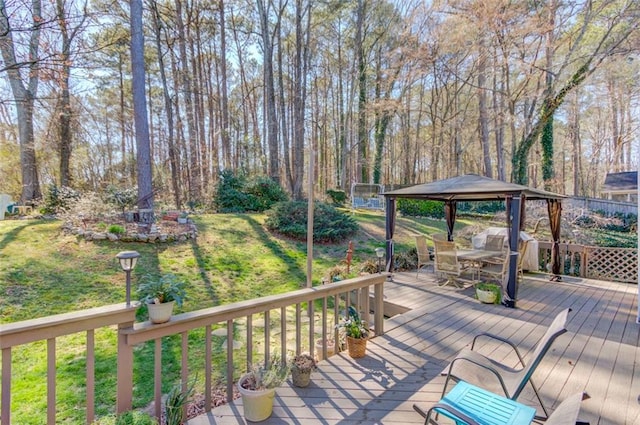 deck featuring outdoor dining space, a lawn, and a gazebo