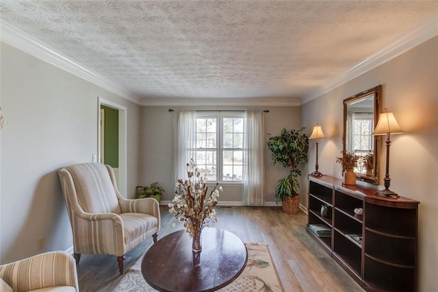 living area featuring a textured ceiling, light wood finished floors, baseboards, and crown molding