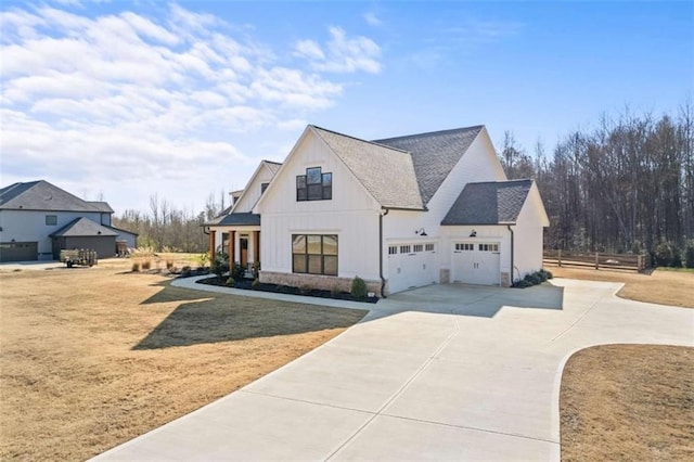 view of front facade with roof with shingles, concrete driveway, a front lawn, a garage, and board and batten siding