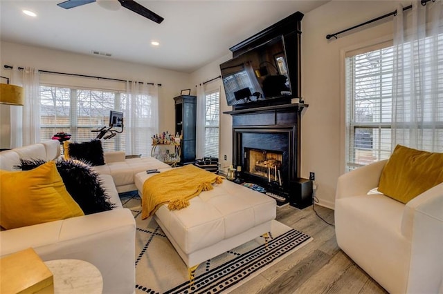 living room with a fireplace, light hardwood / wood-style flooring, and ceiling fan