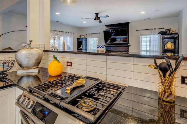 kitchen featuring white cabinetry, ceiling fan, stainless steel range with gas cooktop, and decorative backsplash