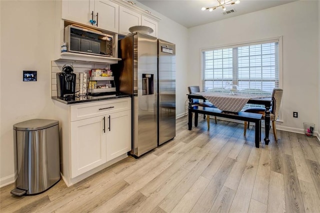 kitchen featuring stainless steel fridge with ice dispenser, black microwave, a notable chandelier, light hardwood / wood-style floors, and white cabinets