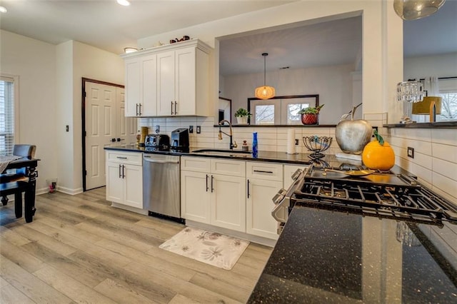 kitchen with appliances with stainless steel finishes, sink, hanging light fixtures, and white cabinets