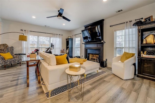 living room with a large fireplace, ceiling fan, and light hardwood / wood-style flooring