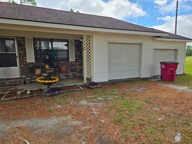 view of side of property featuring brick siding, roof with shingles, and a garage