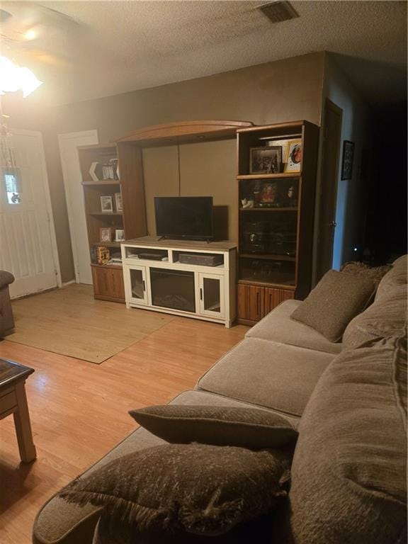 living area featuring light wood-type flooring and a textured ceiling