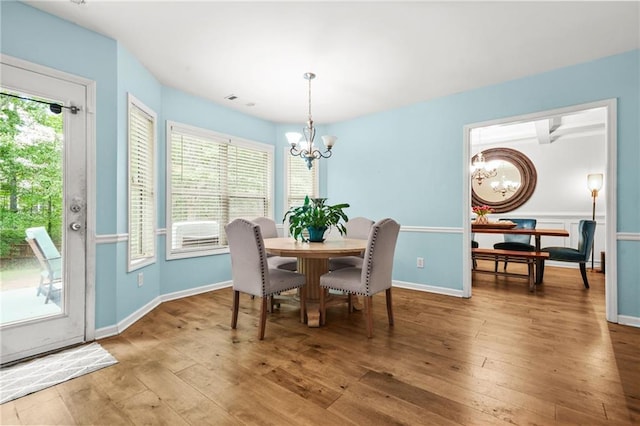dining room with a chandelier, hardwood / wood-style floors, and baseboards