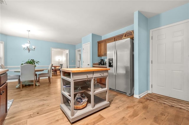 kitchen with stainless steel fridge with ice dispenser, brown cabinetry, light wood-style flooring, and a chandelier