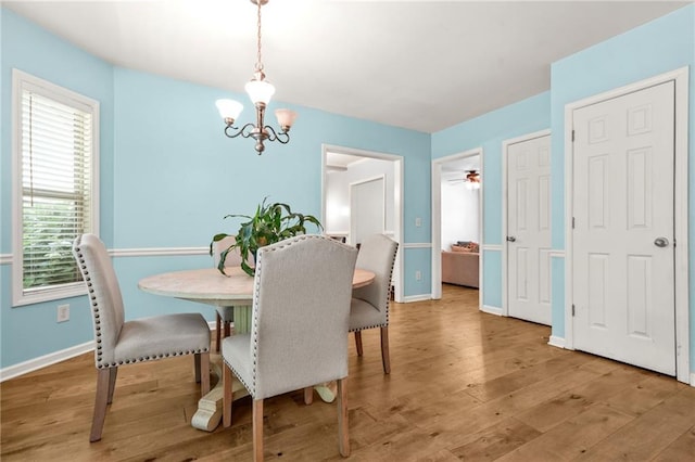 dining space featuring a chandelier, baseboards, and wood finished floors