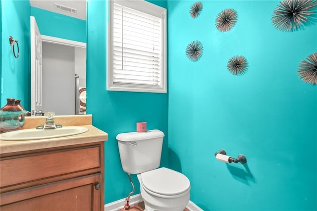 bathroom featuring toilet, vanity, and baseboards