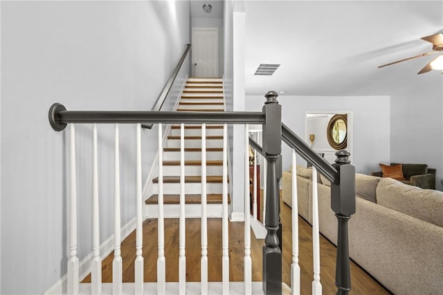 staircase with ceiling fan and wood finished floors