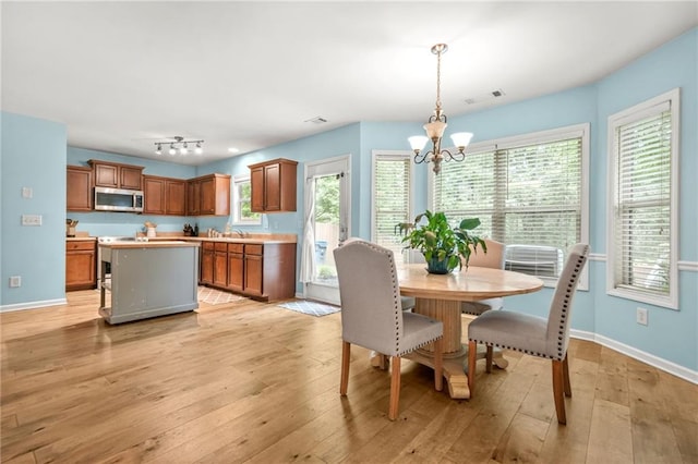 dining space with a chandelier, light wood-style flooring, baseboards, and plenty of natural light